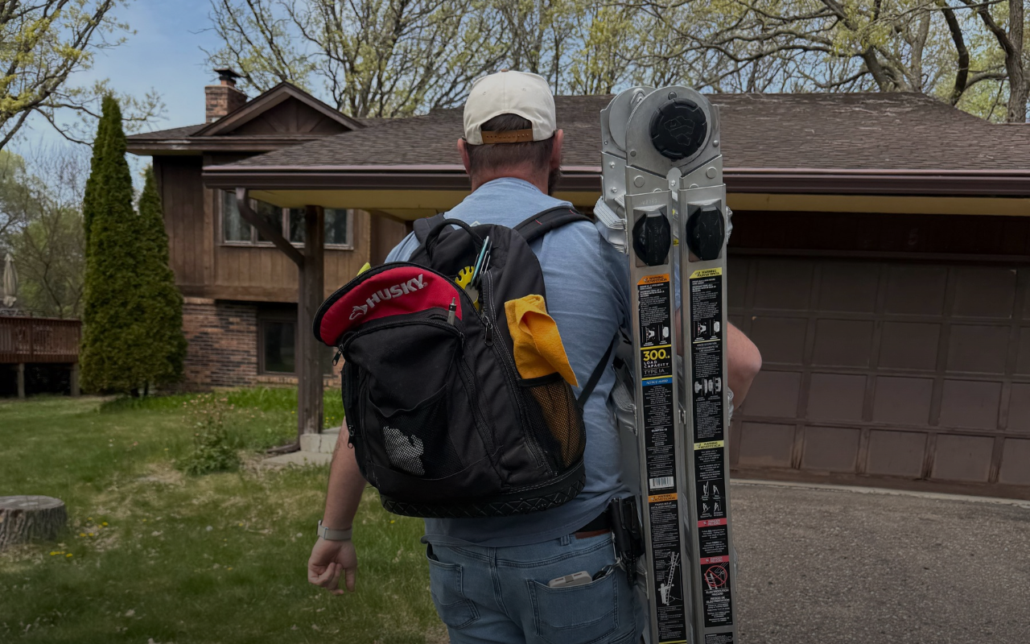 Inspector carrying a ladder into a home